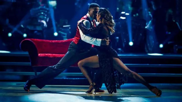 Harry, wearing a waistcoat, shirt and tie, and his partner Karen, who wears a velvet and chiffon mid-length black dress
