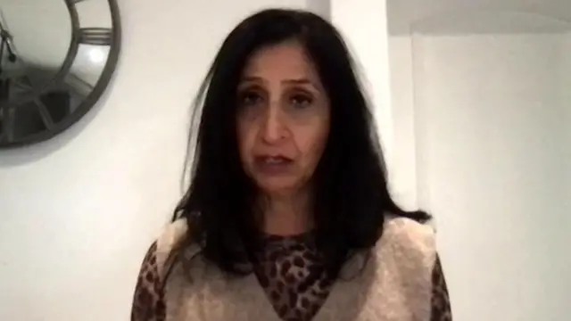 A woman in a knitted vest with long black hair
