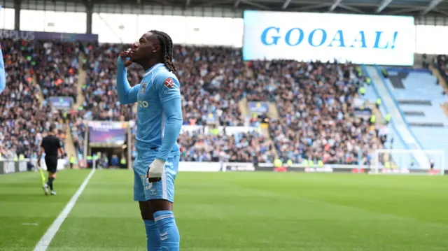 Brandon Thomas-Asante celebrates with "Goooooalll" shown on the scoreboard in the background