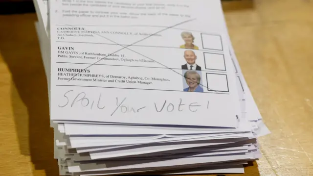 A stack of ballot papers with a big X through the top paper and has 'spoil your vote' written on it.