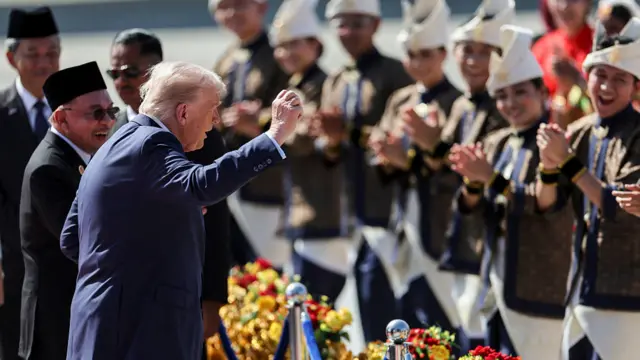 US President Donald Trump joins performers for a dance during the welcome ceremony next to Malaysia's Prime Minister Anwar Ibrahim as he arrives on Air Force One at Kuala Lumpur International Airport
