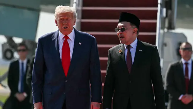 US President Donald Trump speaks with Malaysia's Prime Minister Anwar Ibrahim as he walks from Air Force One upon arrival at Kuala Lumpur International Airport