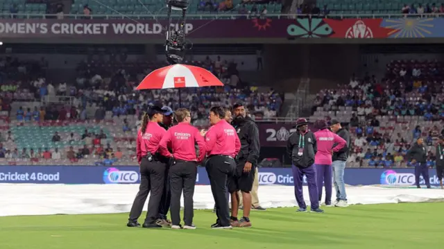 The match officials inspect the pitch during a rain delay