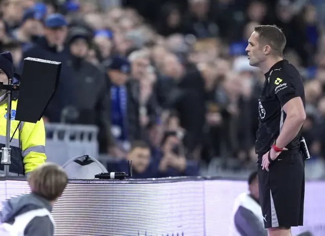 Referee Craig Pawson performs a VAR check during the Premier League match at Hill Dickinson Stadium, Everton.