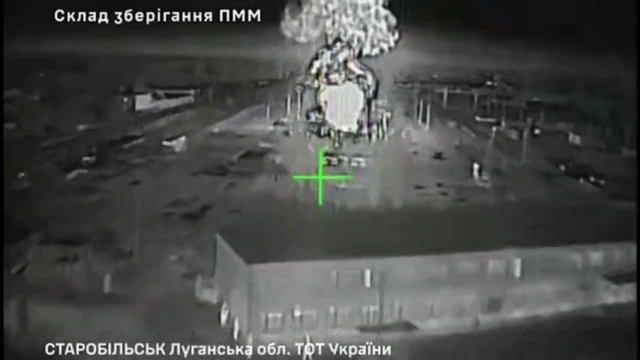 A infrared drone video showing a large fireball and a smoke plume after a drone strike, a building which looks like a warehouse is in the foreground