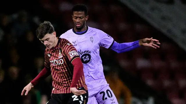 Justin Obikwu of Lincoln City vies for possession with Jenson Metcalfe of Bradford City