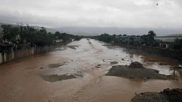 muddy water flowing through a concrete basin between neighborhoods