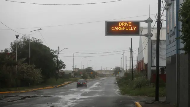 single car on wet road with stormy sky in background