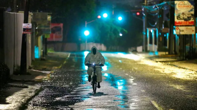 A man wearing a protective suit cycles on a street, as Hurricane Melissa approaches, in Kingston, Jamaica, October 27, 2025