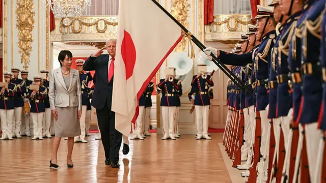 Trump chào cờ quốc gia Hoa Kỳ với sự giúp đỡ của Lực lượng Phòng vệ Nhật Bản tại buổi tiếp tân danh dự, với Takaichi đứng xem ở bên cạnh