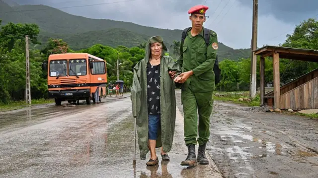 A soldier helps evacuate an elderly woman before the arrival of Hurricane Melissa at Siboney beach, in Santiago de Cuba, on Tuesday