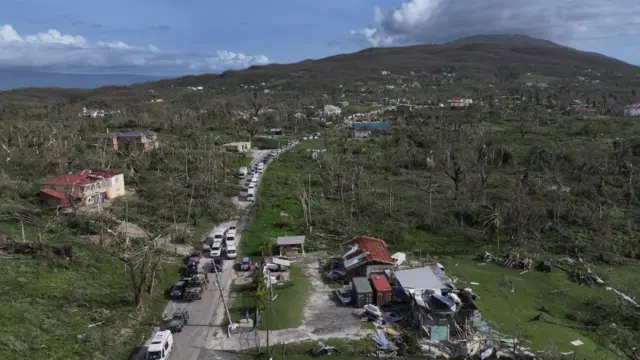 A photo of a road leading up a hill - rubble and fallen trees can be seen