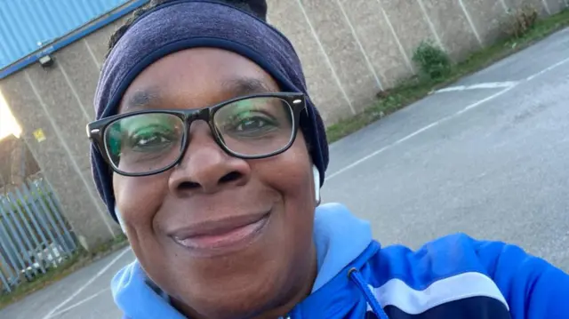 Yvonne Williams is wearing reading glasses and a blue hoodie.