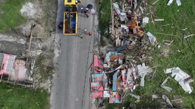 An aerial view of a road with rubble from destroyed buildings on either side