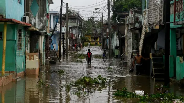 Residents stand in a flooded street, in the aftermath of Hurricane Melissa, in Santiago, Cuba,