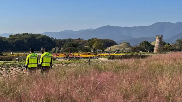 Two police officers in neon yellow coats walking in a field