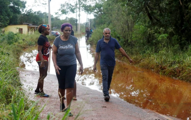 People walk on a flooded road, after Hurricane Melissa made landfall, in Prospect, Manchester