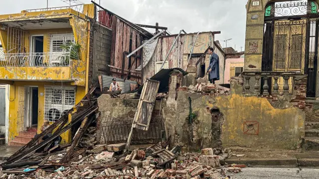 rubble of a collapsed home with men standing on top