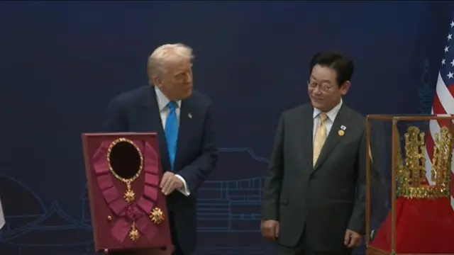 Trump holding a maroon frame with Lee Jae Myung by his side