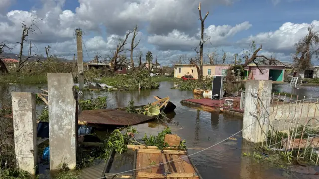 Water submerges a number of residential buildings - doors, buckets and other belongings can be seen floating alongside tree branches