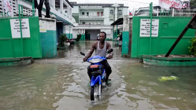 man writing motorcycle through flooded street