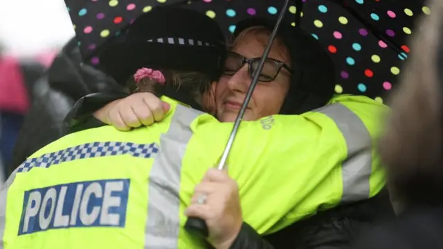 A woman hugs a female police officer.