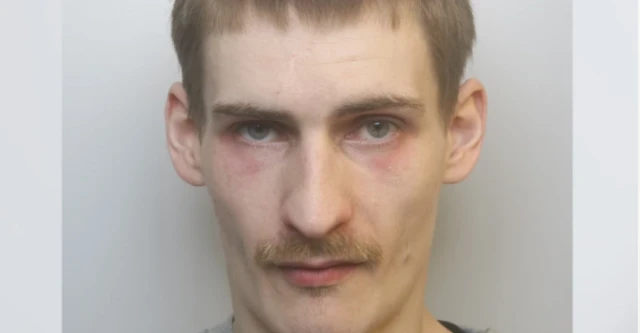 A custody shot of Daniel Gunter. He has dark blonde hair and a moustache.