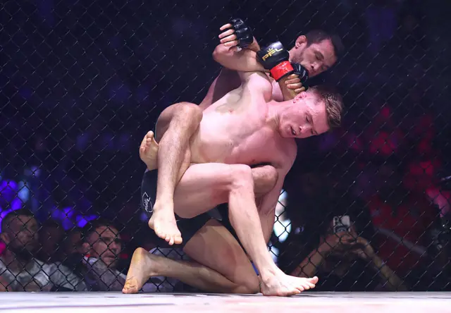 Usman Nurmagomedov attempting a submission on the back of Paul Hughes