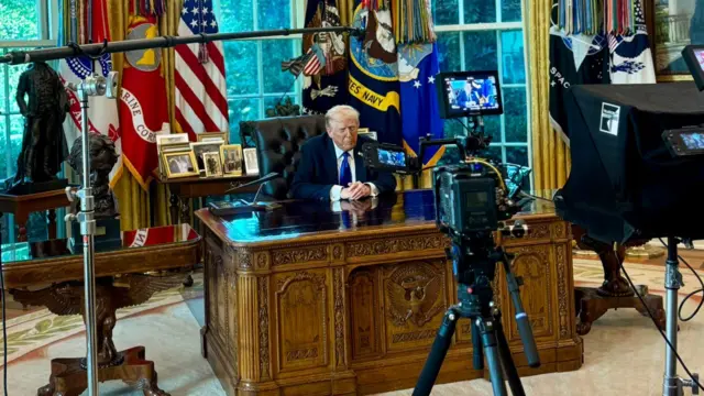 Trump sitting behind desk records a television message