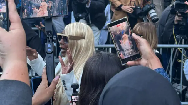 Janice Combs outside court with multiple people filming her on phones