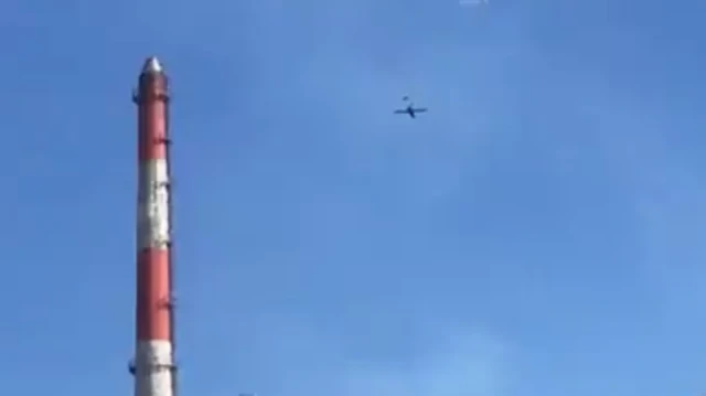 On the left a red and white chimney and top of frame is a drone