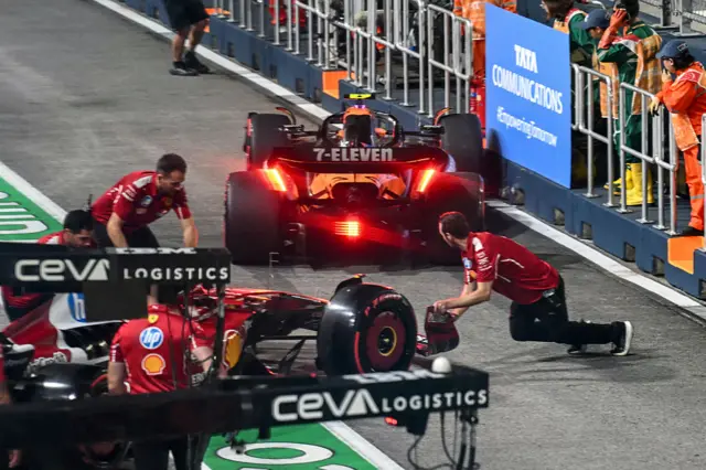 Lando Norris hits the wall after Charles Leclerc crashes into him in the pit lane