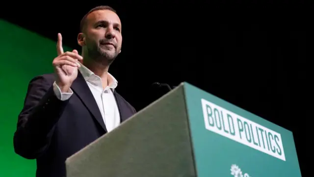 The Green Party leader at a podium that says 'bold politics'