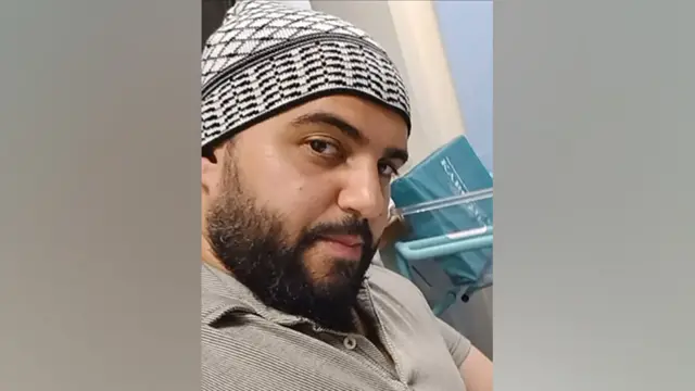 Jihad Al-Shamie is seen wearing a black and white hat and a grey T-shirt