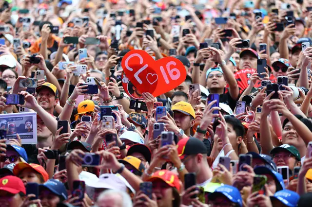 Fans in Singapore hold up signs in the fanzone
