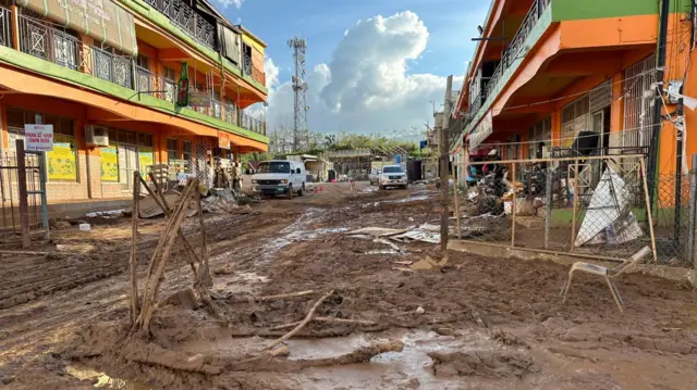 mud-covered road with trash and debris piled up