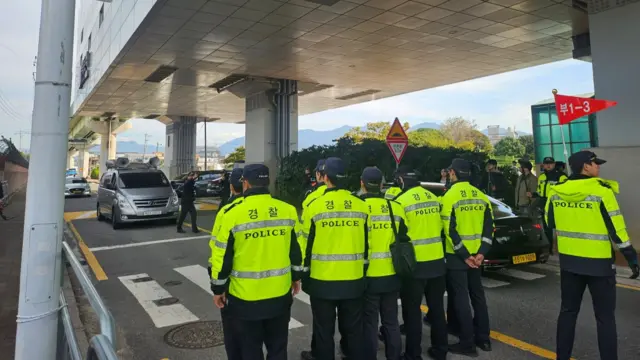 Rows of police in neon yellow jackets standing in the middle of a road