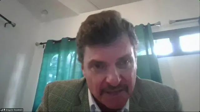 A man in a checked tweed jacket looks at the camera