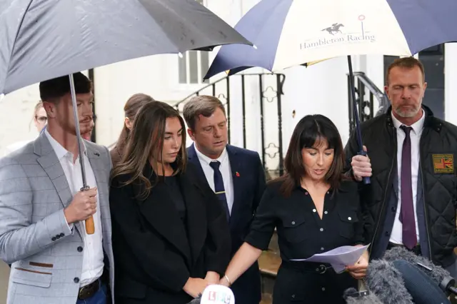 Leighann McCready stands in a group of about six people who wear dark clothing and smart suits. She is speaking to the media outside the Wiltshire and Swindon Coroner's Court in Salisbury, after the coroner gave their conclusion at inquest of the teenage soldier.