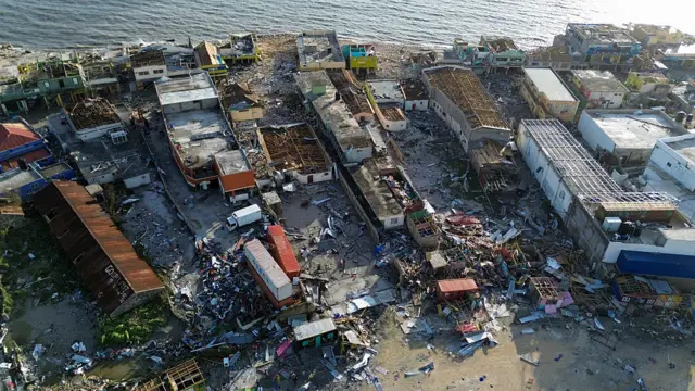 aerial shot of wreckage of homes and rubble by the sea