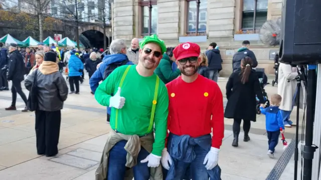Two men are dressed up as Luigi and Mario from the Super Mario Bros game franchise