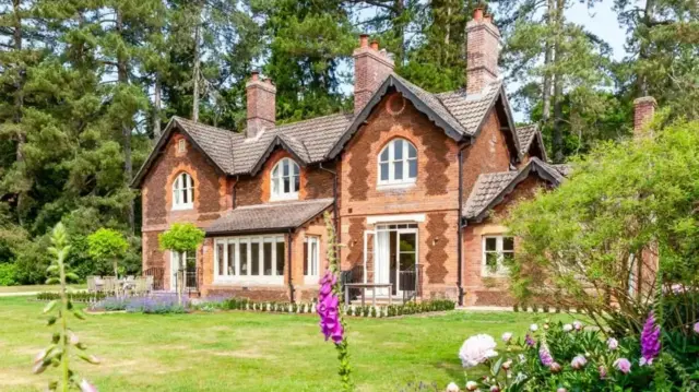 Facade of Gardens House in summer with foxgloves in bloom in the foreground