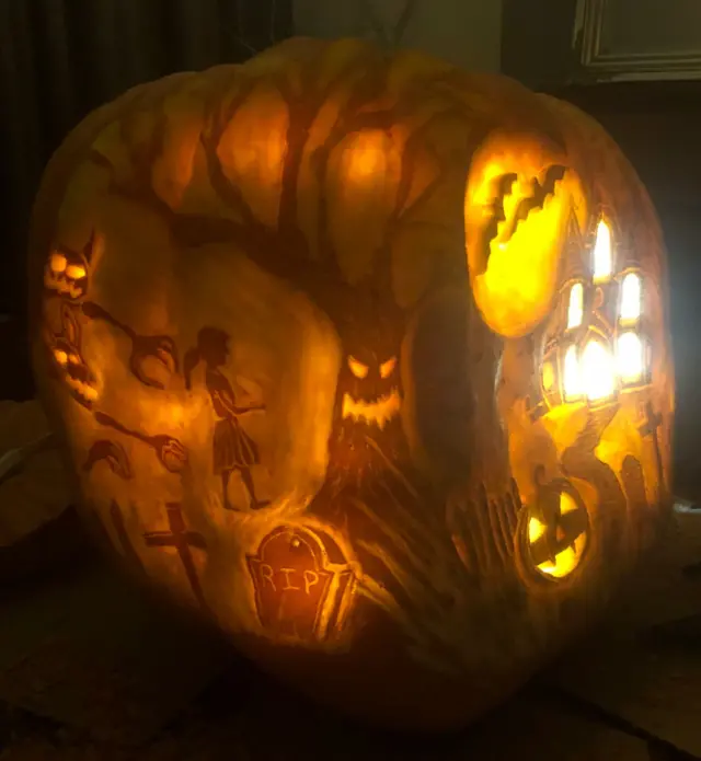 A detailed carving into the side of an enormous pumpkin.
