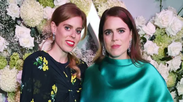 Princess Beatrice (L) smiles as she stands next to Princess Eugenie (R)