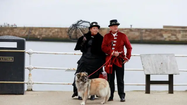 A couple in fancy dress stand by the waterfront in Whitby, England.