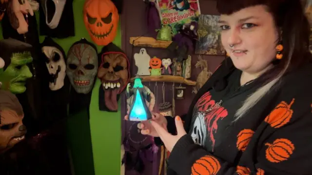 A woman poses with a Halloween decoration.