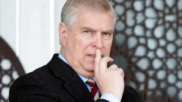 Andrew Mountbatten Windsor's head and shoulders. He holds a finger up to his lips.