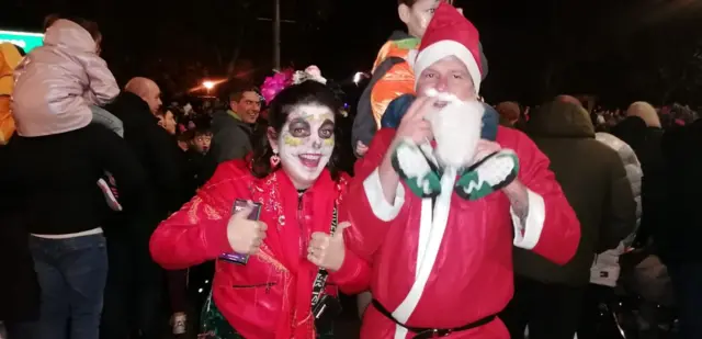 two adults and a young boy are dressed in red santa suits