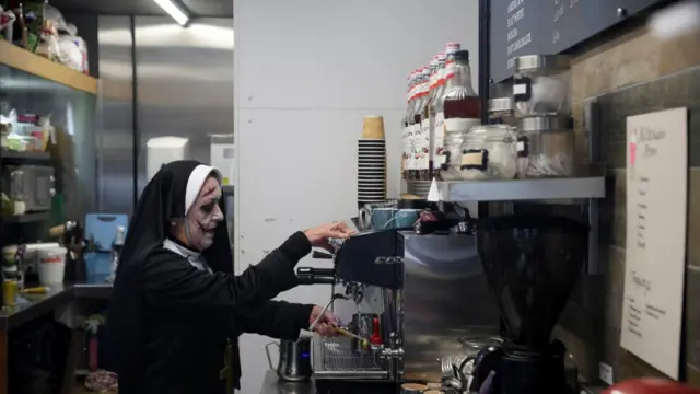 A woman dressed in costume makes a coffee in a Whitby cafe.