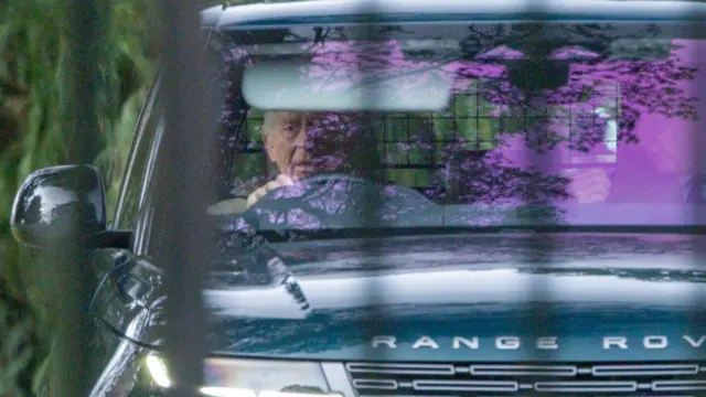 The King driving in a black range rover